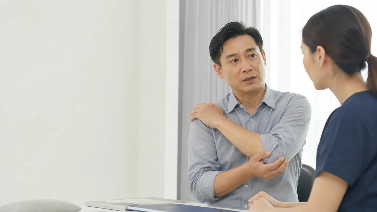 東亞男性在諮詢時輕觸手肘